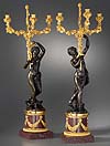 A superb pair of Louis XVI gilt and patinated bronze and red porphyry three-light figural candelabra after a model attributed to Clodion